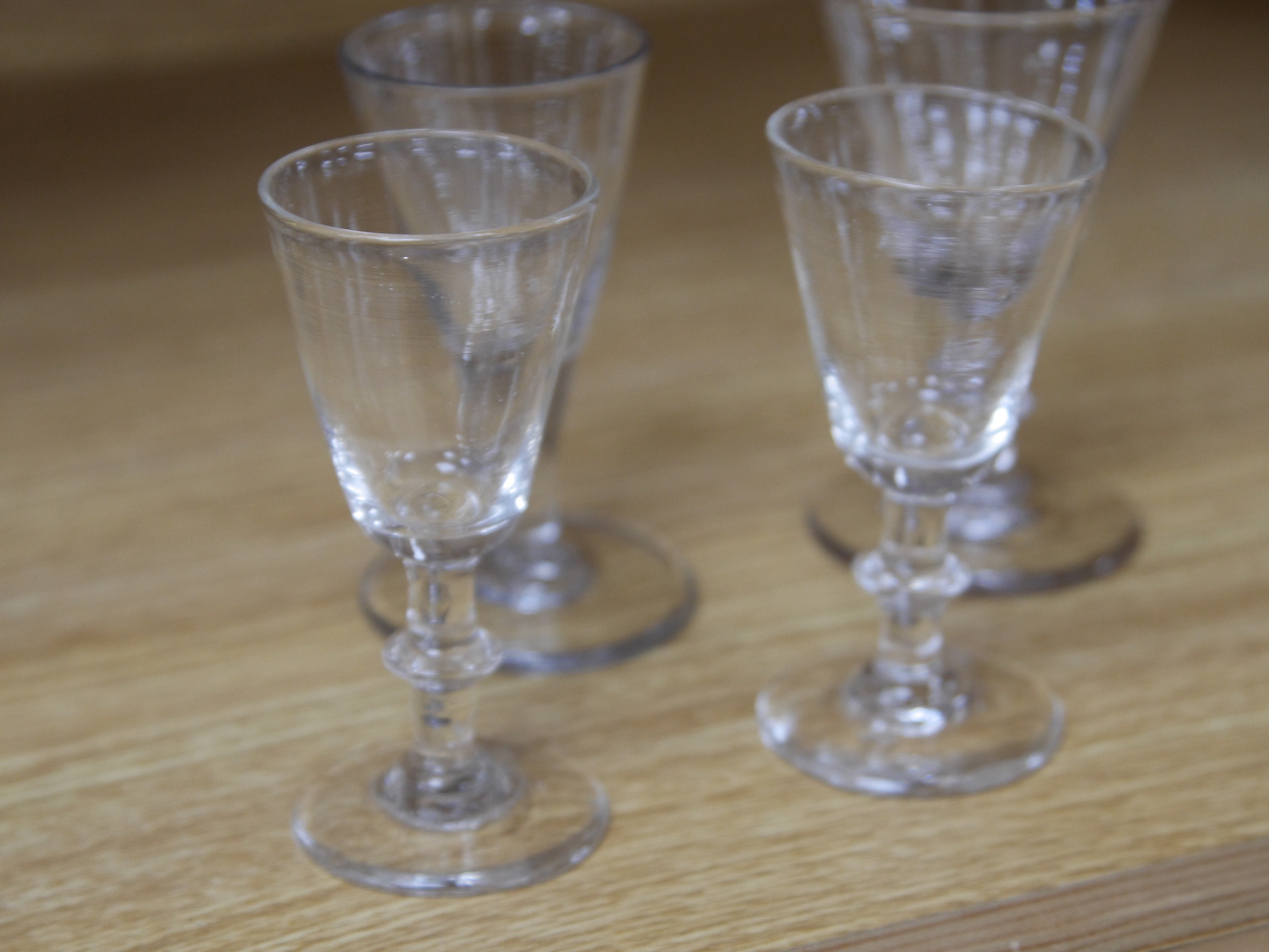 Four late 18th century ale wine and dram glasses, tallest 10.5cm. Condition - largest glass has a fine chip to rim